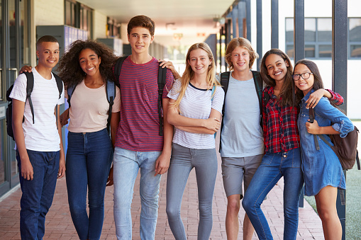 Grupo de adultos jóvenes de pie en un pasillo de la escuela
