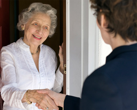 A volunteer shaking hands with an elderly woman